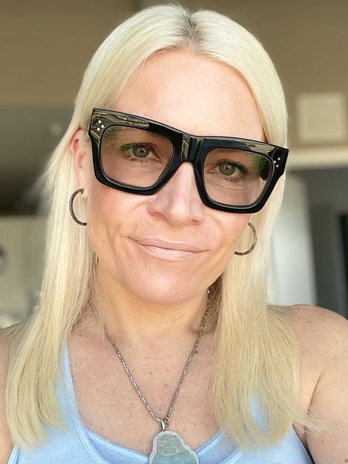 blonde woman with thick black frame glasses